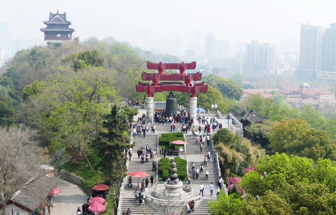 胜。 黄鹤楼始建于三国时代,唐代诗人崔颢在此题下《黄鹤楼》一诗,李白在此写下《黄鹤楼送孟浩然之广陵》,历代文人墨客在此留下了许多千古绝唱,使得黄鹤楼自古以来闻名遐迩。 黄鹤楼坐落在海拔六十多米的蛇山顶,京广铁路的列车从楼下呼啸而过。黄鹤楼高5层,总高度51.4米,外部有60个翘角向外伸展,屋面用黄色琉璃瓦覆盖,整个建筑具有独特的民族风格,散发出汉族传统文化的精神、气质、神韵。进入底层大厅,是一幅表现"白云黄鹤"的故事的大型陶瓷壁面画。据传古代一位叫辛氏的人开店卖酒,一名落魄文人常来喝酒